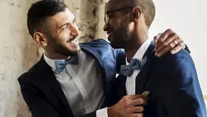 Two men in suits and bow ties smiling with joy